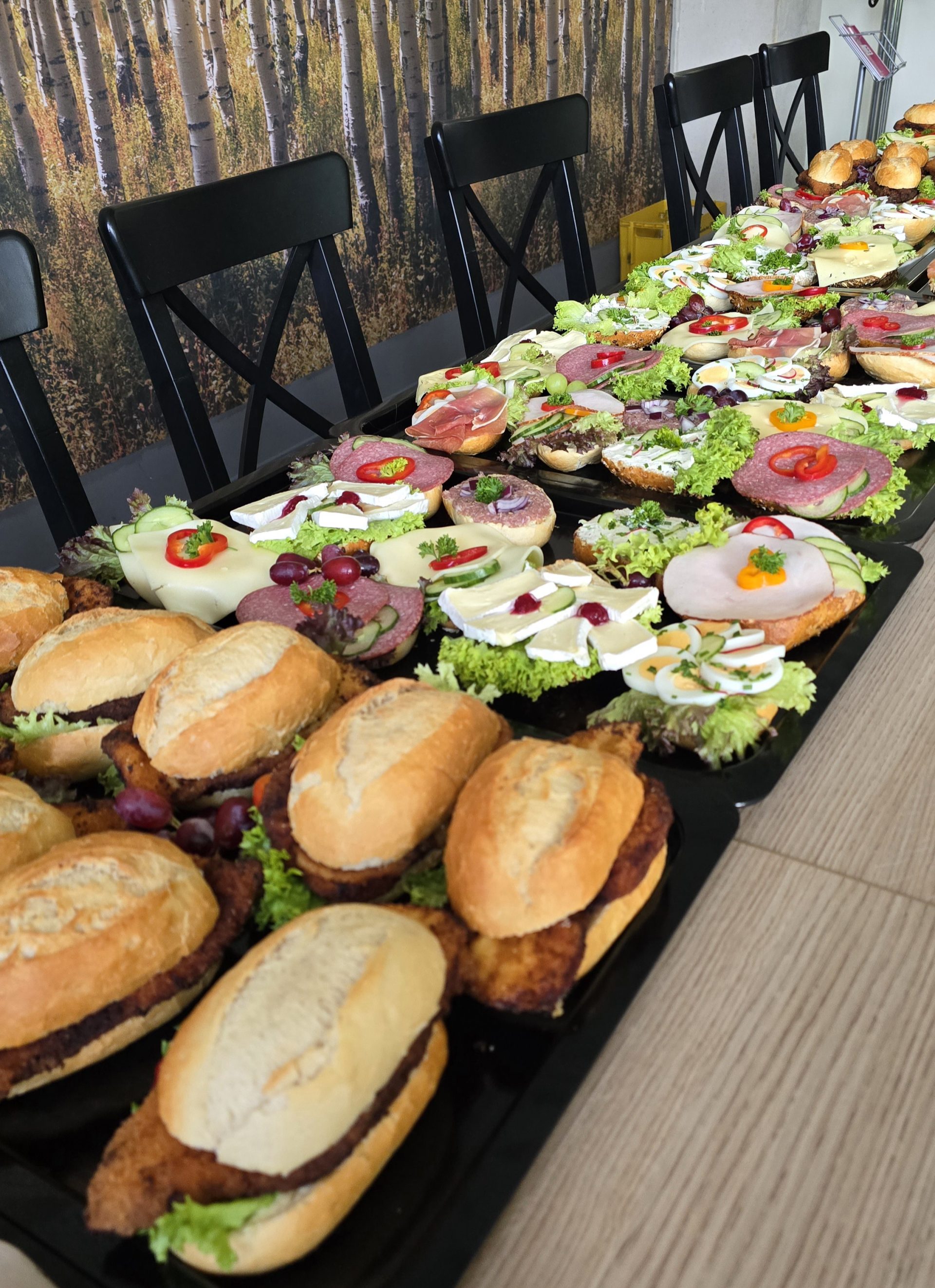 Lange Reihe von belegten Brötchen und Schnitzelbrötchen auf einem Tisch.