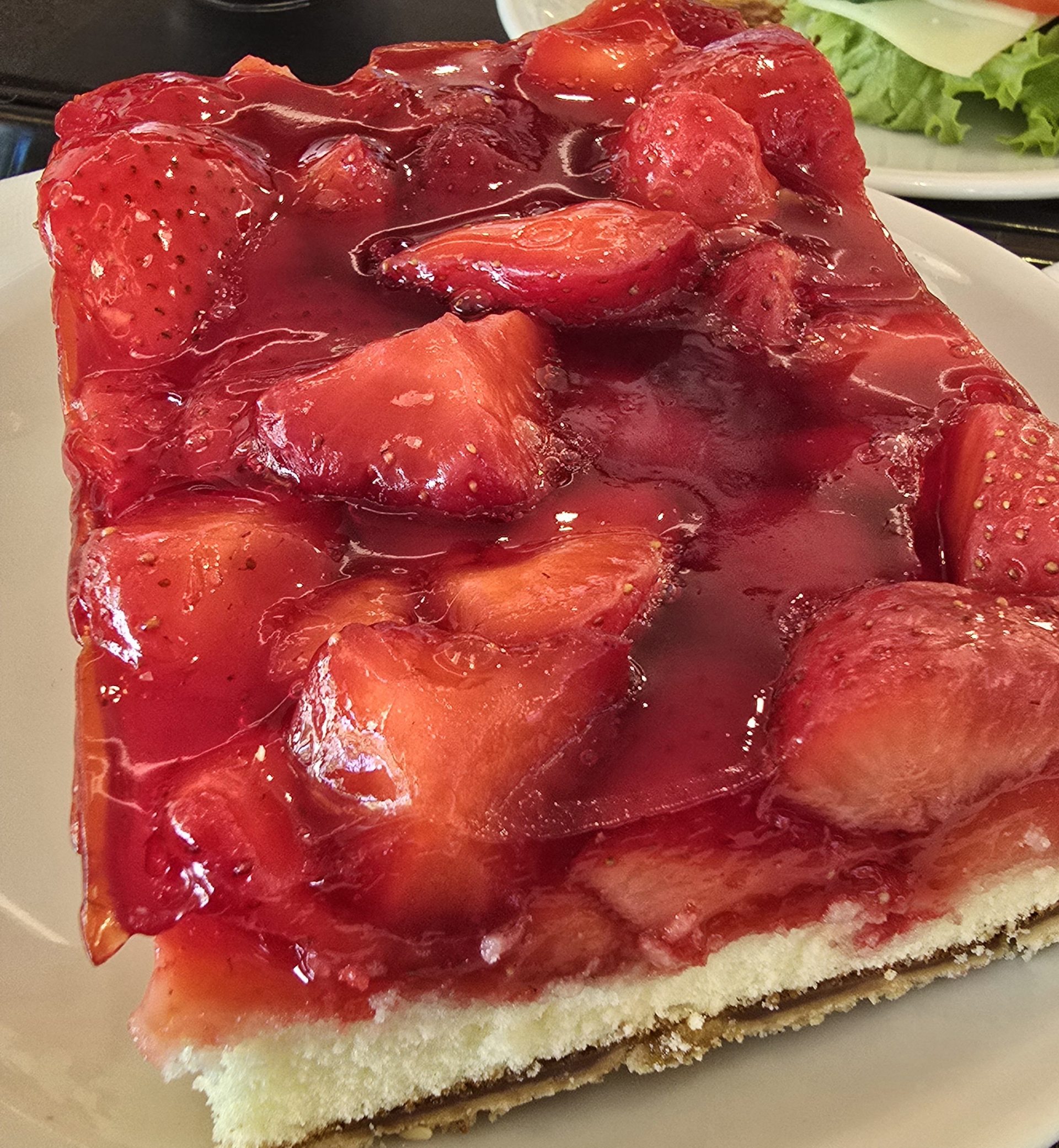 Nahaufnahme eines Stücks Erdbeerkuchen mit glänzendem Guss.
