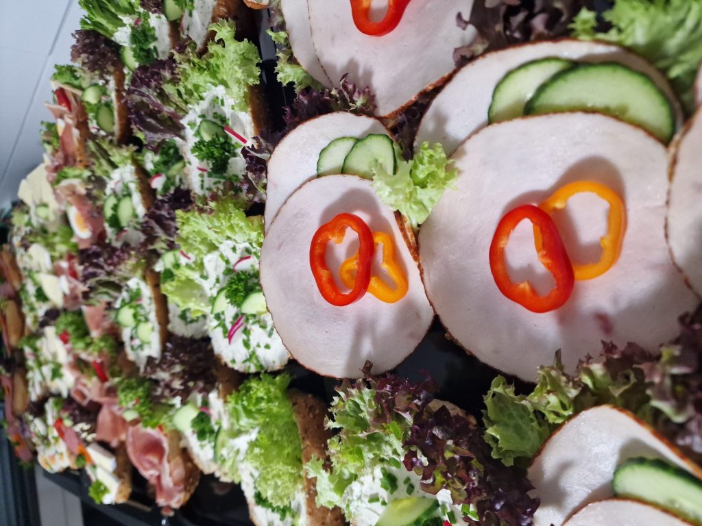 Anrichteteller mit belegten Brötchen, darunter eine Nahaufnahme von Aufschnitt mit Paprikaringen.