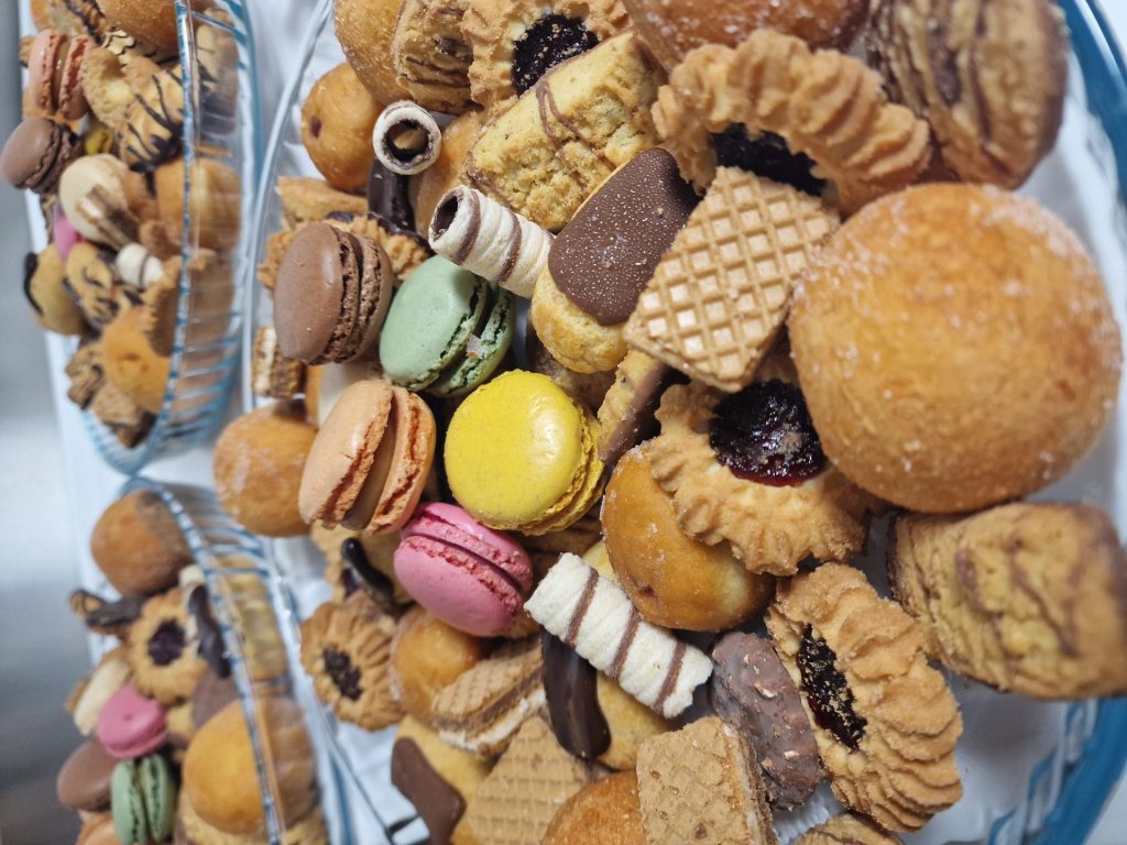 Nahaufnahme von Macarons und vielfältigem Kleingebäck auf Glasplatten.